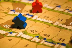 Board games meeples standing on score track close-up photo