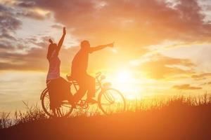 silueta de dulce pareja joven enamorada tiempo feliz en bicicleta foto