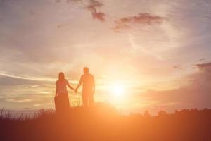 una silueta de un hombre y una mujer tomados de la mano, caminando juntos. foto