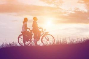 silueta de dulce pareja joven enamorada tiempo feliz en bicicleta foto