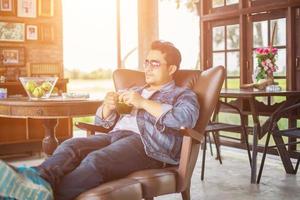 joven con smartphone sonriendo relajándose en el café. foto