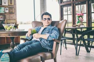 Young man with smartphone smiling relaxing at cafe. photo