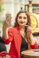 Happy young girl taking selfie at cafe outdoors. photo