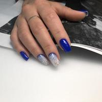 elegante manicura femenina azul de moda. manos de una mujer con manicura azul en las uñas foto