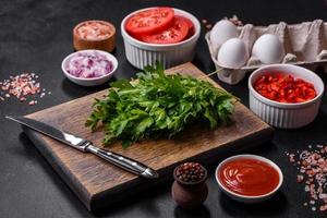Ingredients for making shakshuka, dishes with fried eggs with tomato sauce, spices and herbs photo