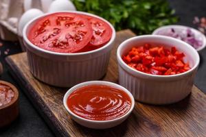 Ingredients for making shakshuka, dishes with fried eggs with tomato sauce, spices and herbs photo