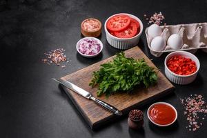 Ingredients for making shakshuka, dishes with fried eggs with tomato sauce, spices and herbs photo