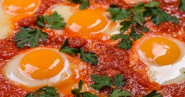 Shakshuka, a dish with fried eggs with tomato sauce, sweet pepper, garlic, onions, spices and herbs photo