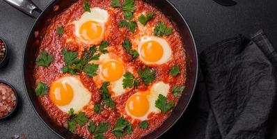 Shakshuka, a dish with fried eggs with tomato sauce, sweet pepper, garlic, onions, spices and herbs photo