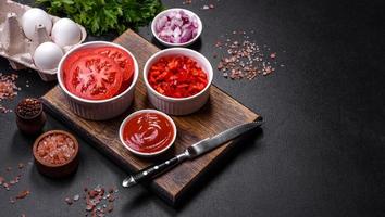 Ingredients for making shakshuka, dishes with fried eggs with tomato sauce, spices and herbs photo