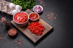 Ingredients for making shakshuka, dishes with fried eggs with tomato sauce, spices and herbs photo