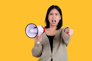 Friendly young woman holds a megaphone in her hands and points her finger at the viewer on a yellow background. Hiring concept, help wanted. Banner. photo