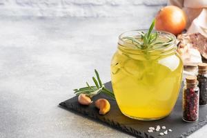 Homemade beef bone and vegetable broth with turmeric seasoning in a glass jar for storage and carrying. Healthy food with collagen and amino acids. Copy space. photo