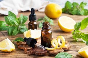 Lemon citrus fruit essential oil and mint, aromatherapy oil natural organic cosmetic on rustic wood background. photo