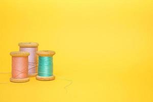 Three multi-colored spools of thread on a yellow background photo