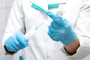 the doctor draws the medicine into a syringe for injection photo