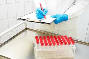 next to the treatment table with a rack of test tubes, the doctor writes a referral for analysis photo