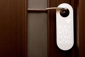 closed door, do not disturb sign hanging on the handle, busy with home work photo