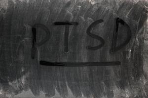 the word PTSD - post traumatic stress disorder handwritten on full frame background and texture of dusty black surface of an old LCD screen photo