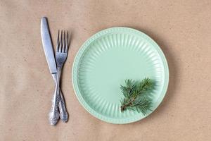 Holiday table setting with branch of christmas tree, empty plate and decorations. New year flat lay food concept photo