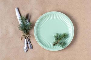 Holiday table setting with branch of christmas tree, empty plate and decorations. New year flat lay food concept photo