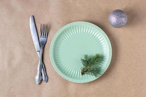 Holiday table setting with branch of christmas tree, empty plate and decorations. New year flat lay food concept photo