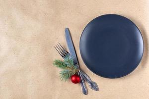 Holiday table setting with branch of christmas tree, empty plate and decorations. New year flat lay food concept photo