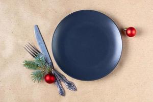 Holiday table setting with branch of christmas tree, empty plate and decorations. New year flat lay food concept photo