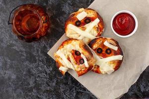 Mini pizza as mummy for kids with cheese, olives and ketchup. Funny crazy Halloween food for children. photo