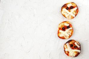 mini pizza como momia para niños con queso, aceitunas y ketchup. divertida comida loca de halloween para niños foto