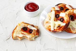 Mini pizza as mummy for kids with cheese, olives and ketchup. Funny crazy Halloween food for children photo