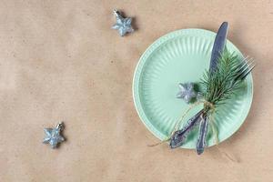 Holiday table setting with branch of christmas tree, empty plate and decorations. New year flat lay food concept photo