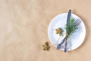 Holiday table setting with branch of christmas tree, empty plate and decorations. New year flat lay food concept photo