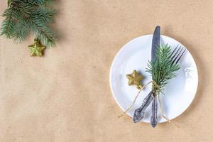 Holiday table setting with branch of christmas tree, empty plate and decorations. New year flat lay food concept photo