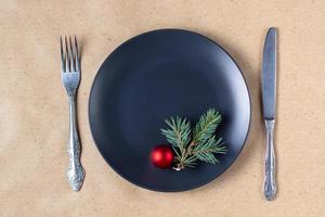 mesa de vacaciones con rama de árbol de navidad, plato vacío y decoraciones. concepto de comida plana de año nuevo foto