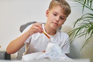 Schoolboy makes creative project in form of papier mache mountain. photo