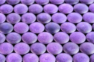 close-up background of many purple organic compacted powder tablets laid tight in one layer on flat surface photo