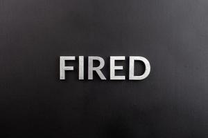 the word fired laid with white brushed metal letters on flat black surface photo