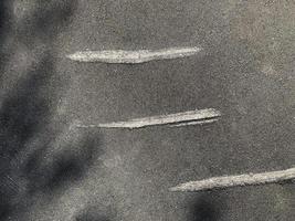 Dark asphalt texture with three old scratched stripes, abstract background. photo