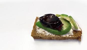 Healthy food, cereal bread toast with avocado, cream cheese and sun-dried plums on white background, for breakfast or keto diet, copy space photo