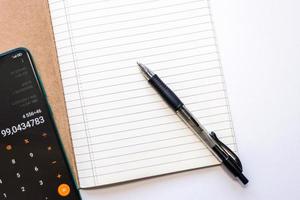 toma superior de un cuaderno forrado abierto con un bolígrafo y un teléfono móvil foto