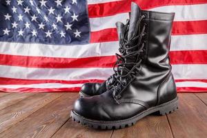 black ankle boots in front of US flag on wooden surface photo