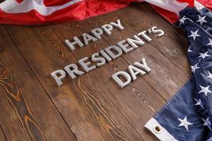 words happy presitdents day laid with real letters on wooden board near US flag photo