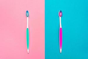 primer plano de cepillos de dientes de plástico azul y rosa con cerdas rosas y azules sobre fondo rosa y azul foto