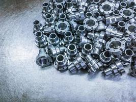 A pile of shiny steel parts after cnc turning and milling operations on steel sheet - close-up with selective focus. photo