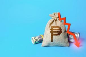 Philippine peso money bag and arrow down. Falling economy. Drop in profits. Decrease in interest rate deposit rate. Inflation. Low real incomes, economic difficulties. Recession and depression photo