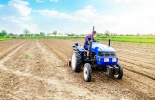 A farmer riding a tractor on a farm field. Farming and work in the agricultural industry. Cultivating land soil for further planting. Using technology to facilitate work and increase efficiency photo