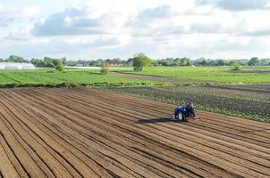 un tractor monta en un campo agrícola. aflojando la superficie, cultivando la tierra para plantar más. el agricultor en un tractor con fresadora afloja, muele y mezcla el suelo. ganadería y agricultura. foto