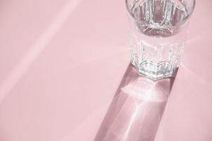 vaso de agua en rosa, luz solar y sombra, espacio de copia foto