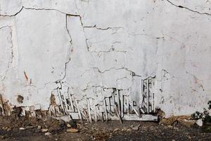 poor wattle and daub cracked stucco wall with white plaster photo